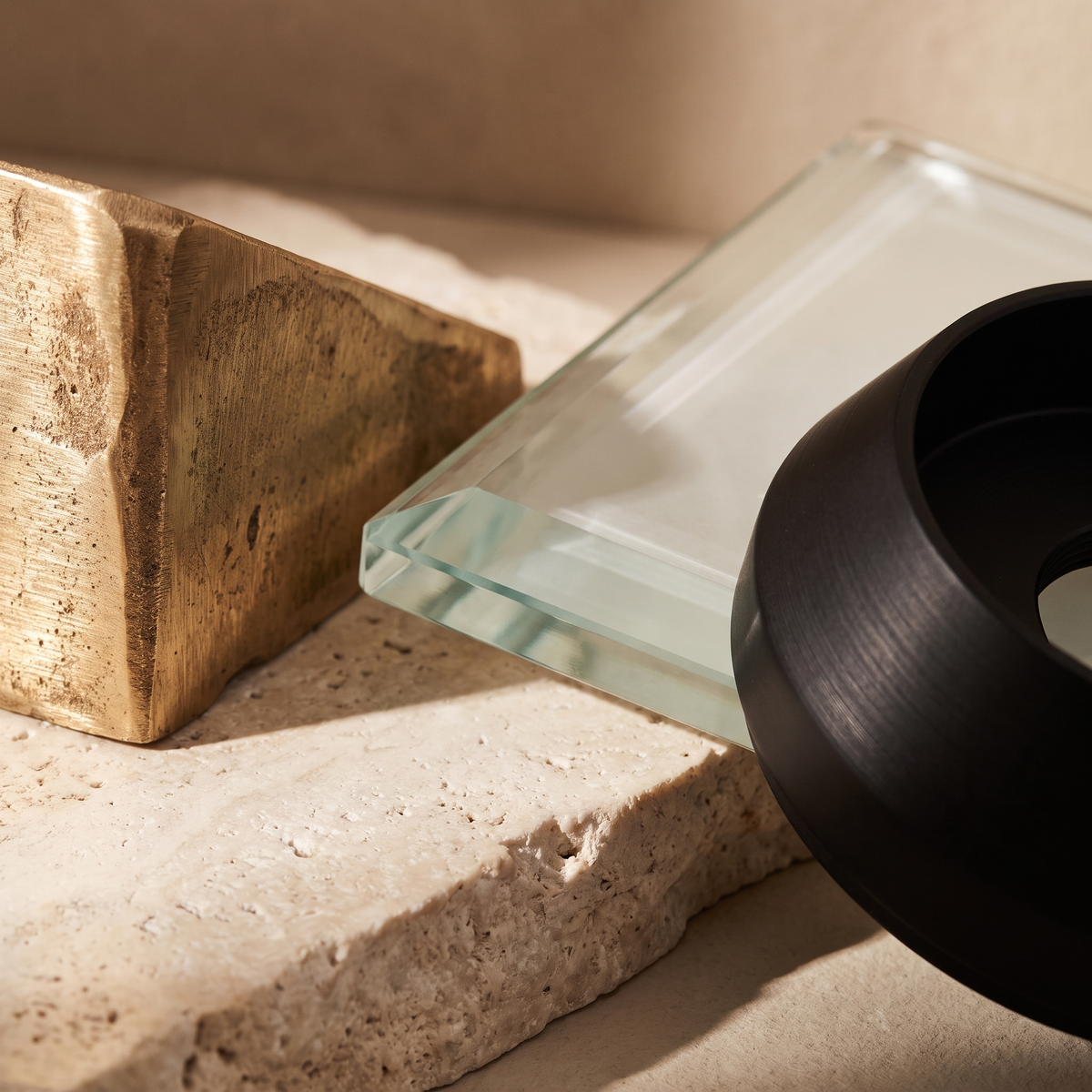Close up of solid brass, tempered glass and matte black metal on pale stone