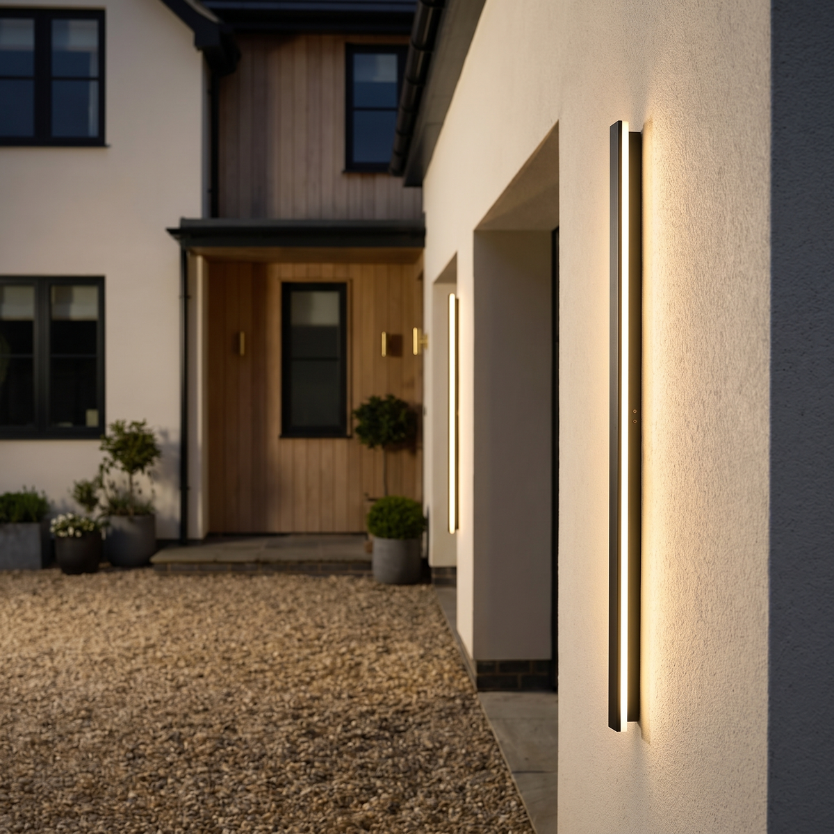 Pair of Lumera wall lights on a plaster facade in the evening